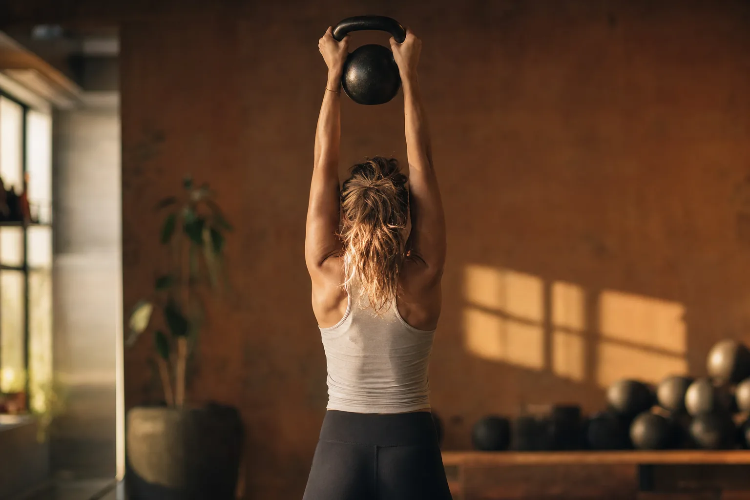 A boutique fitness member mid-workout, warm editorial studio setting